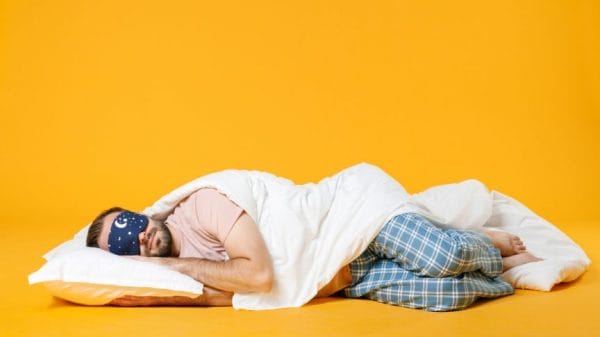 a man sleeps on his side against a yellow background sleep quality