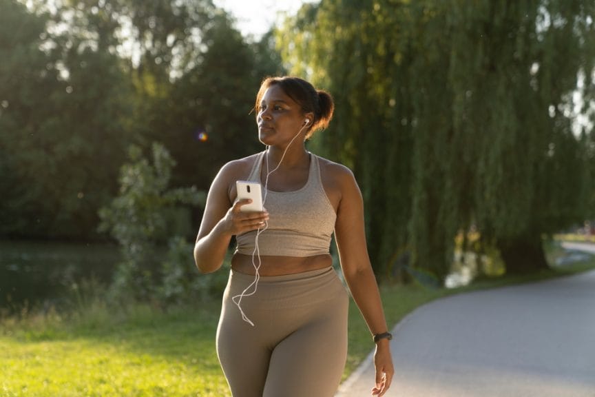 plus size african american girl with headphones going for a walk sunset