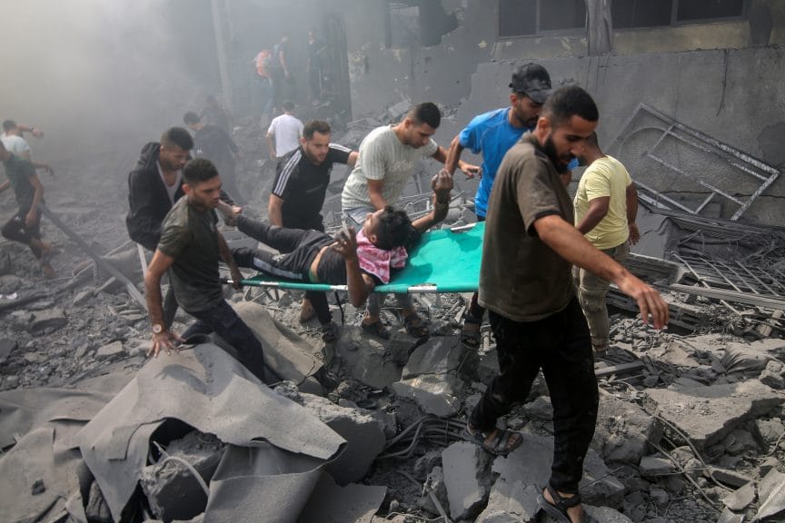 A group of Palestinians carry a wounded person through the rubble.