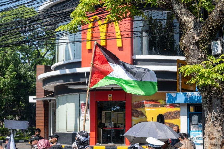 A group of protesters waving the Palestinian flag outside of a McDonalds.