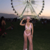 Woman standing in front of a Ferris wheel in a pink bedazzled cowboy outfit.