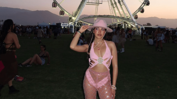Woman standing in front of a Ferris wheel in a pink bedazzled cowboy outfit.