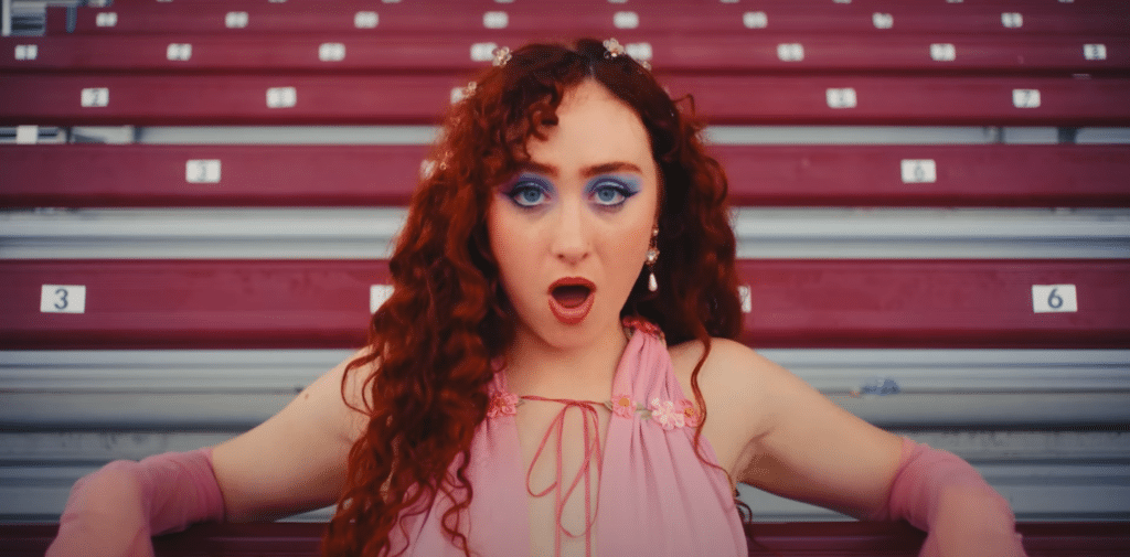 Chappell Roan in her music video "HOT TO GO!" singing in front of bleachers