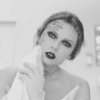 Taylor Swift in black and white in the music video for "Fortnight." She is seen wiping her face and revealing tattoos.