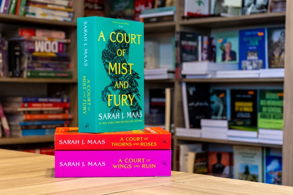 A Court of Mist and Fury fantasy novel in a bookshop on a stack of two other books.