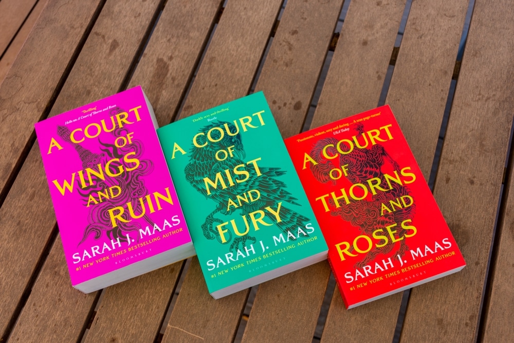 The A Court of Thorns and roses trilogy laid out on a wooden background.