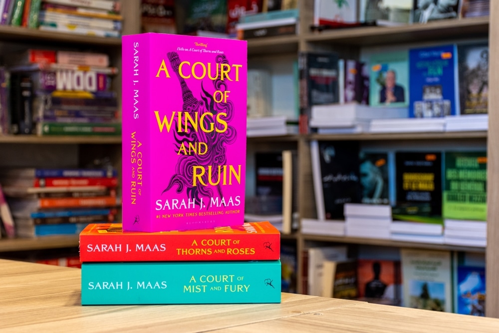 A Court of Wings and Ruin fantasy novel in a bookshop on a stack of two other books From the ACOTAR series by Sarah J. Maas