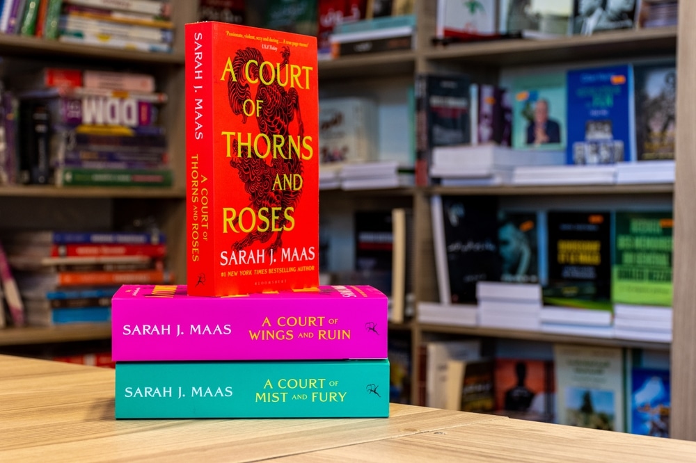 A Court of Thorns and Roses fantasy novel in a bookshop on a stack of two other books.