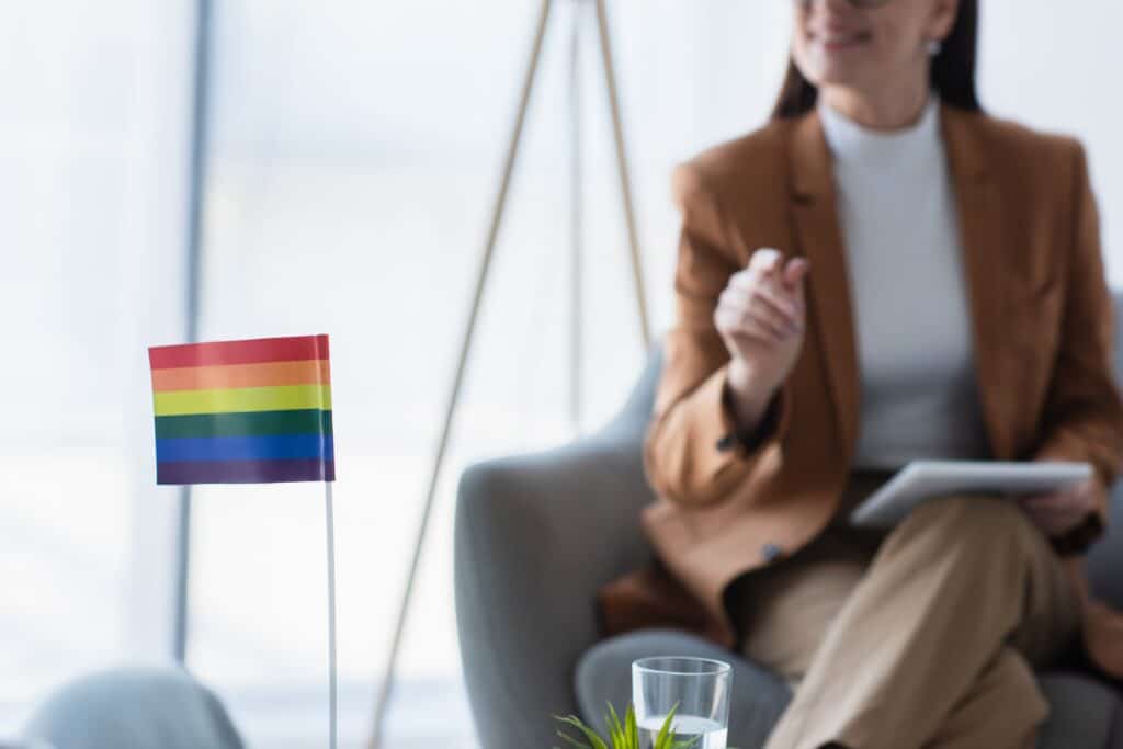 A pride flag sits in the foreground of a psychologist's office.