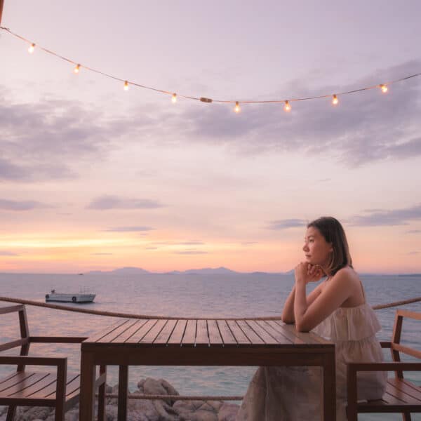 Woman sitting at table all alone with the sunset behind her.