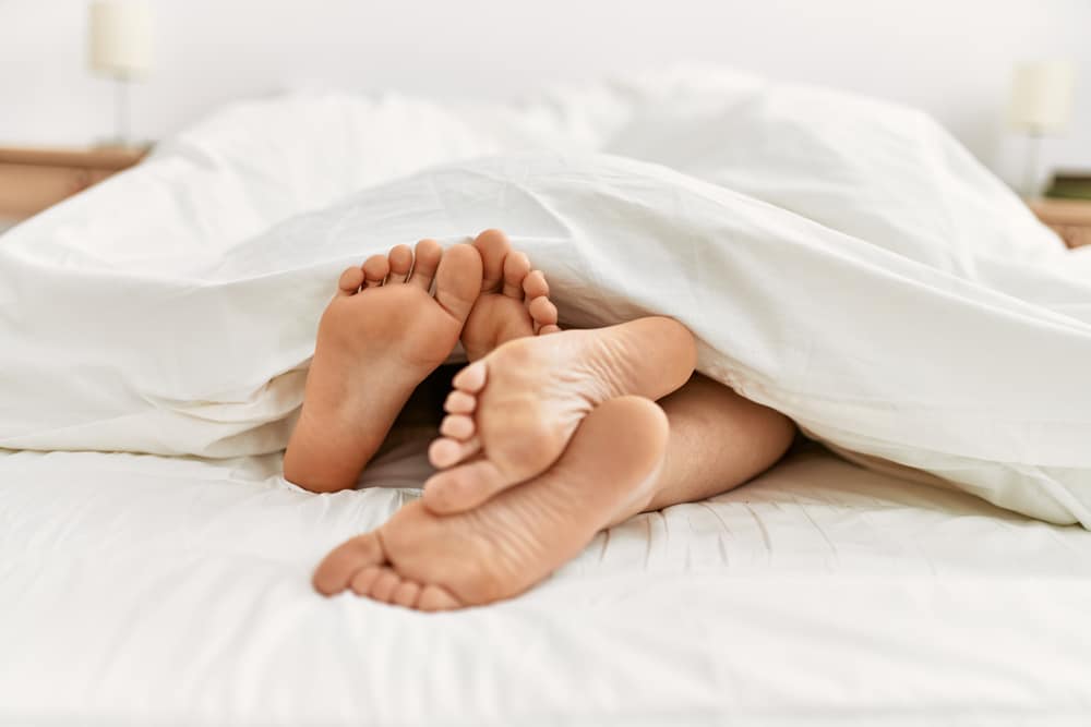 couple's feet cuddling in bed