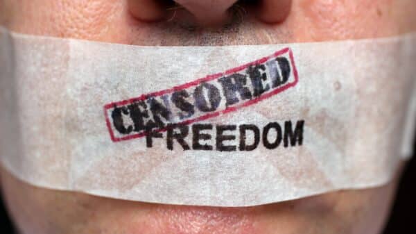 Man with mouth taped over with 'censored freedom' written.