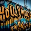 Yellow and blue graffiti that says "Hollywood" is scribbled on the side of a building