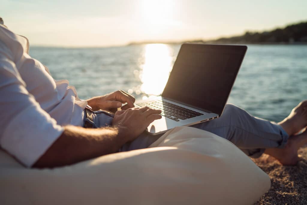 man working on laptop at the beach 